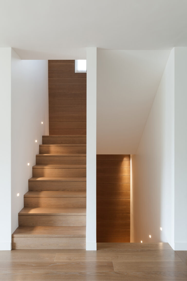 Warm wood staircase with recessed step lighting and high-contrast stair edges, a subtle fall-prevention detail in aging-in-place home design
