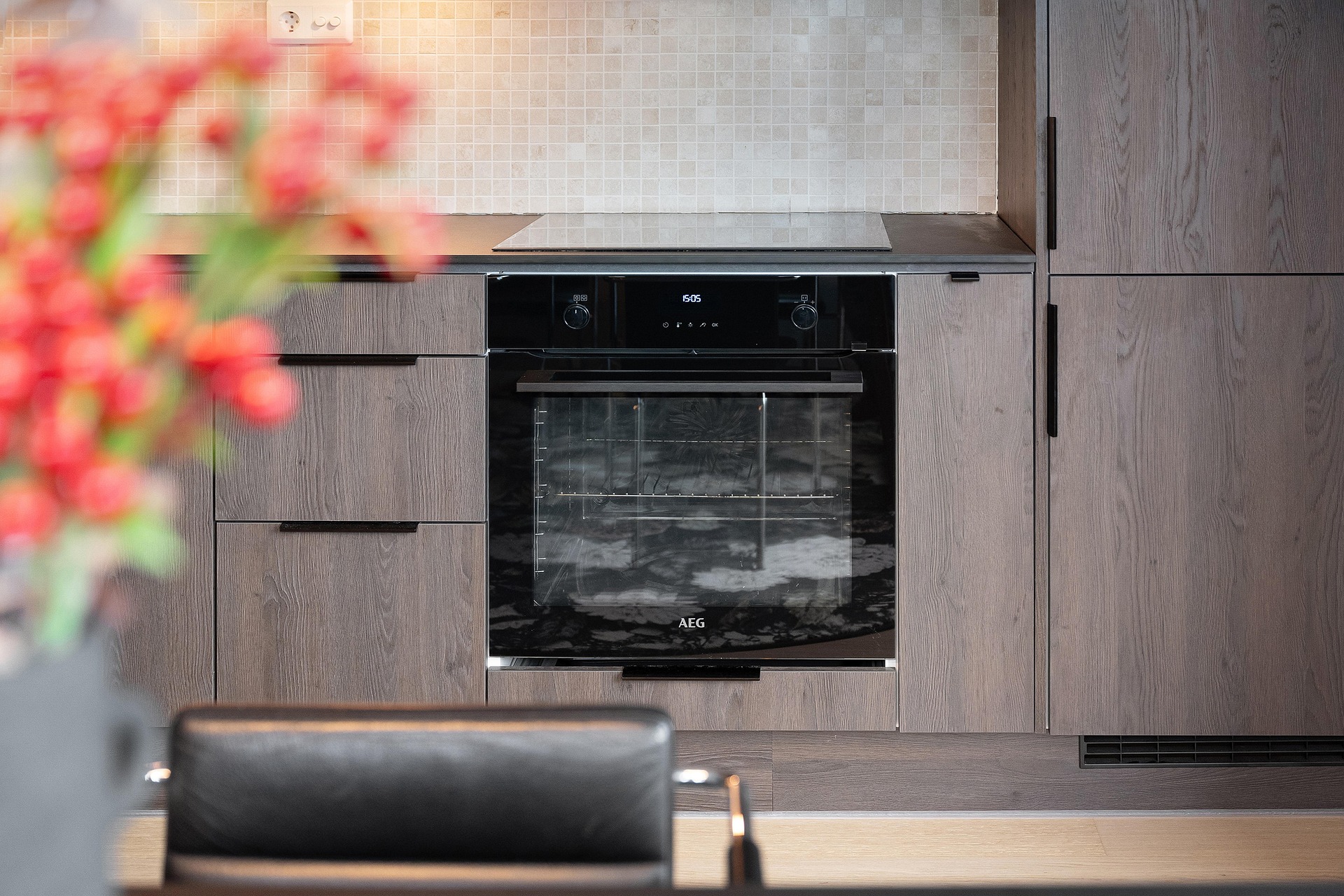 Wall-mounted oven set at chest height in wood-grain cabinetry, reachable without bending