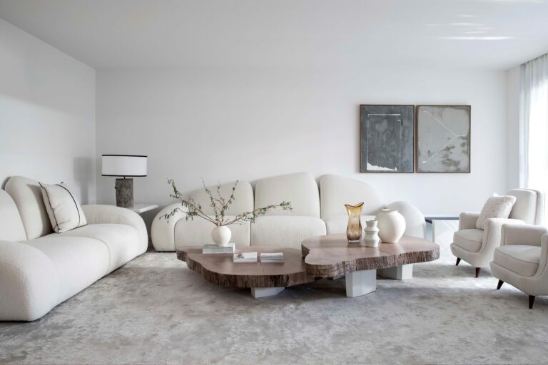 Bright white living room with a curved sectional and round wood coffee tables