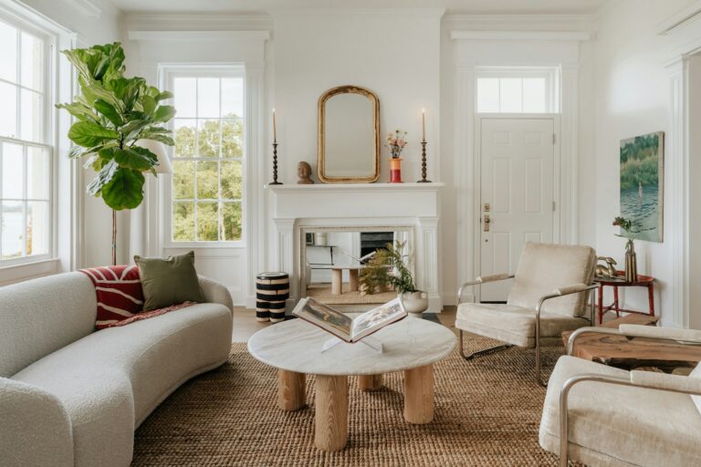 Curated living room with a curved sofa, armchairs, jute rug and fireplace in natural light