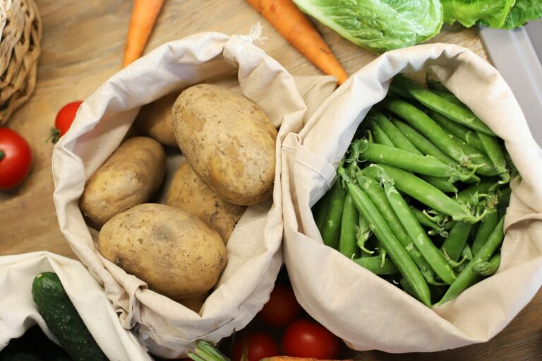 Fresh produce in cotton market bags on a wooden kitchen counter